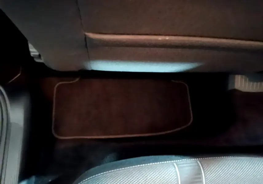 Vue intérieure du plancher arrière avec tapis de sol noir et partie inférieure du siège dans un Volkswagen T-Roc gris foncé.