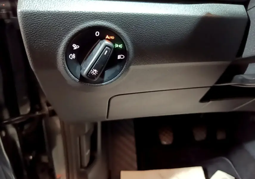 Gros plan sur le bouton de commande des phares dans l’habitacle noir du Volkswagen T-Roc 2022, côté conducteur.