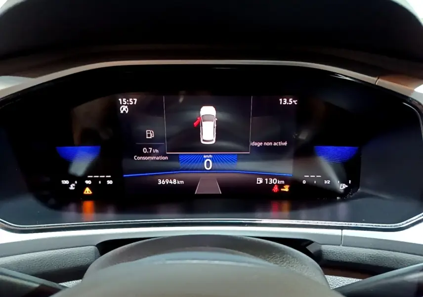 Vue rapprochée du tableau de bord numérique du Volkswagen T-Roc gris foncé, affichant la consommation et la distance restante.