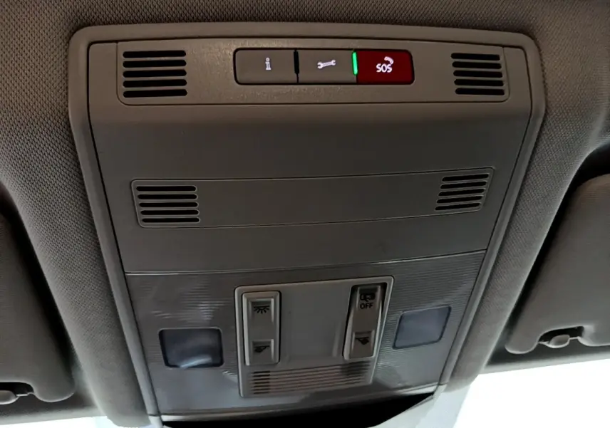 Vue en contre-plongée du panneau de commandes au plafond intérieur gris du Volkswagen T-Roc 2022 avec bouton SOS éclairé en rouge.