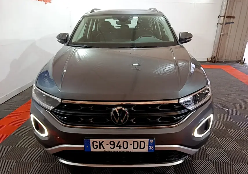 Vue avant d’un Volkswagen T-Roc gris foncé 2022 avec feux diurnes LED allumés dans un garage.