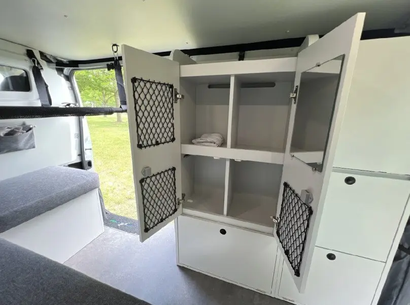 Intérieur du Renault Trafic Fourgon gris 2025, vue sur placard de rangement blanc ouvert avec filet noir, aménagement van.