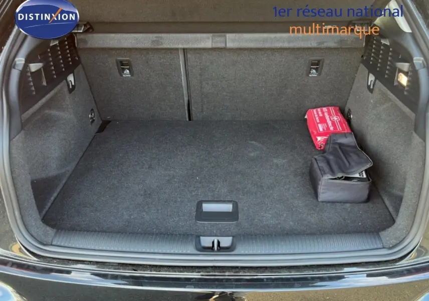 Coffre ouvert de l'Audi Q2 noir mito metal 2023, montrant un espace de chargement propre avec trousse de secours rouge.