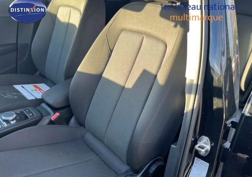 Gros plan sur les sièges avant en tissu noir du côté gauche d'un Audi Q2 noir mito metal 2023 avec porte ouverte.