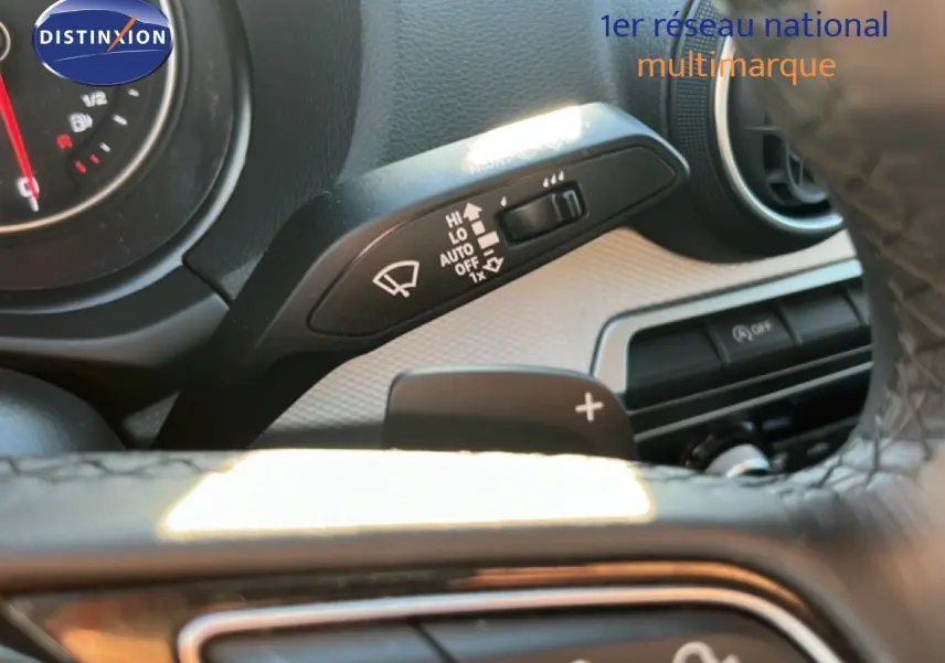 Gros plan sur la commande d'essuie-glace et palette de changement de vitesse derrière le volant d'un Audi Q2 noir Mito Metal.