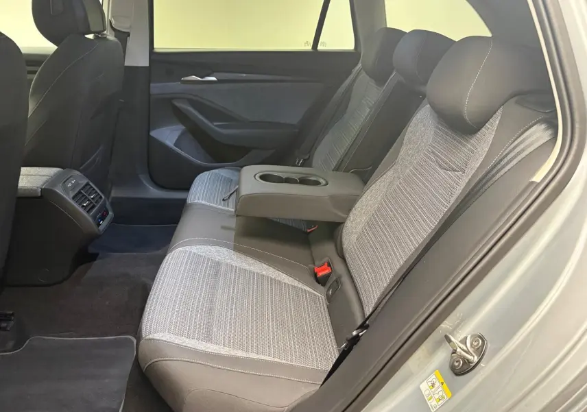 Vue intérieure côté droit des sièges arrière gris clair et foncé du Skoda Superb Combi 2025 avec accoudoir central relevé.