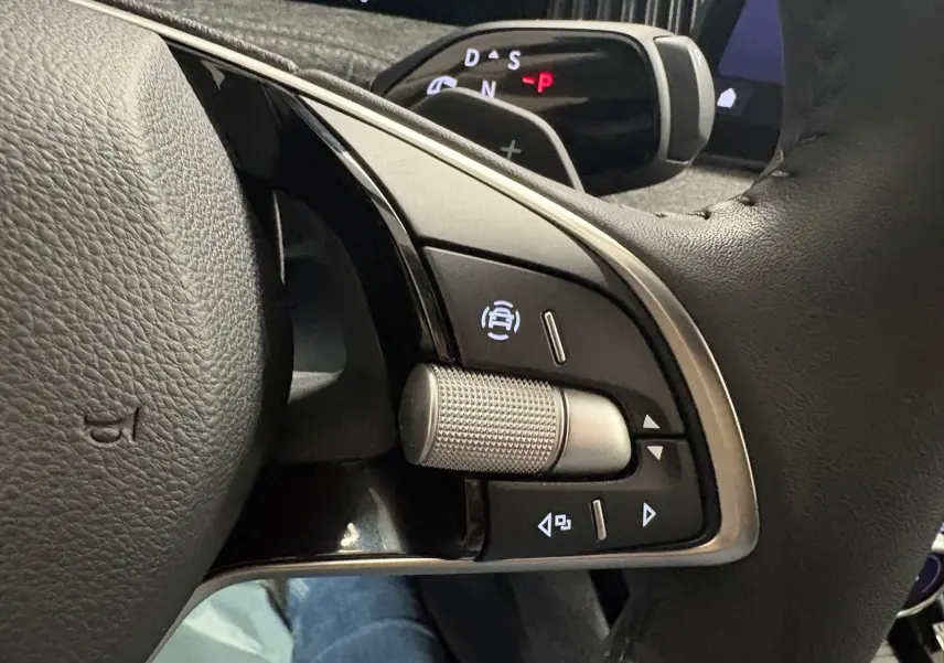 Gros plan sur les commandes à droite du volant en cuir noir du Skoda Superb Combi gris argent 2025, avec molette texturée.