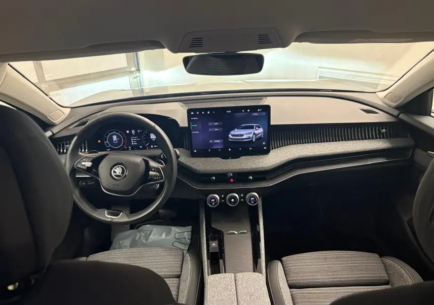 Vue intérieure avant de la Skoda Superb Combi 2025 gris argent, mettant en valeur le tableau de bord moderne et l’écran tactile central.