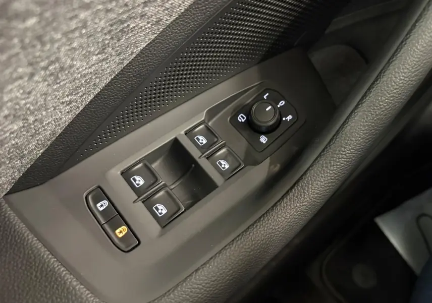 Gros plan sur les commandes des vitres et des rétroviseurs côté conducteur d’un Skoda Superb Combi gris argent 2025.