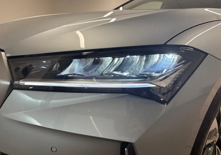Gros plan sur le phare avant droit du Skoda Superb Combi gris argent 2025 avec éclairage LED distinctif.