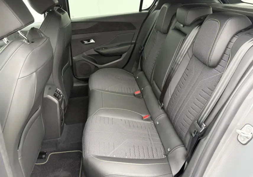 Vue intérieure côté droit des sièges arrière en cuir noir avec surpiqûres vert Adamite de la Peugeot 308 III hybride 2025.