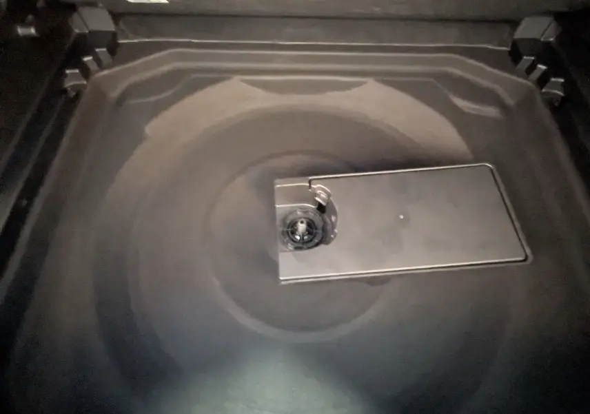 Gros plan sur le coffre noir du Citroën C5 Aircross 2024, montrant la trappe centrale du rangement sous plancher.