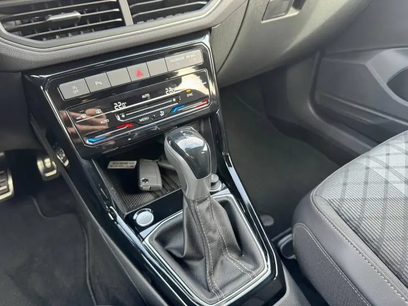Vue rapprochée de la console centrale du Volkswagen T-Cross 2025, avec levier de boîte auto et finition noire brillante.