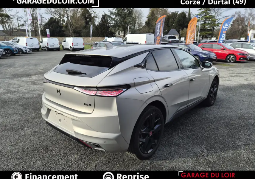 Vue 3/4 arrière droite d'une DS4 beige 2024 avec feux arrière LED et jantes noires sur parking extérieur.