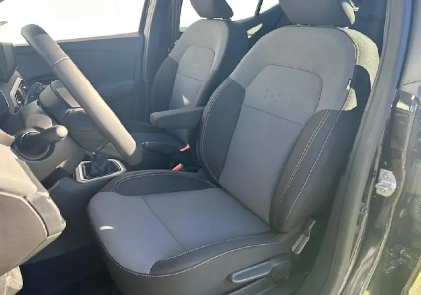 Vue intérieure côté conducteur de la Dacia Sandero III Stepway 2025, sièges gris et noir nacré avec accoudoir.