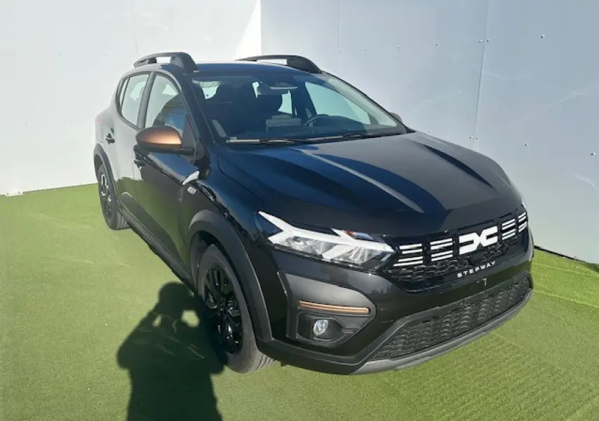 Dacia Sandero III Stepway noir nacré vue 3/4 avant droit avec calandre et barres de toit brun cuivré.