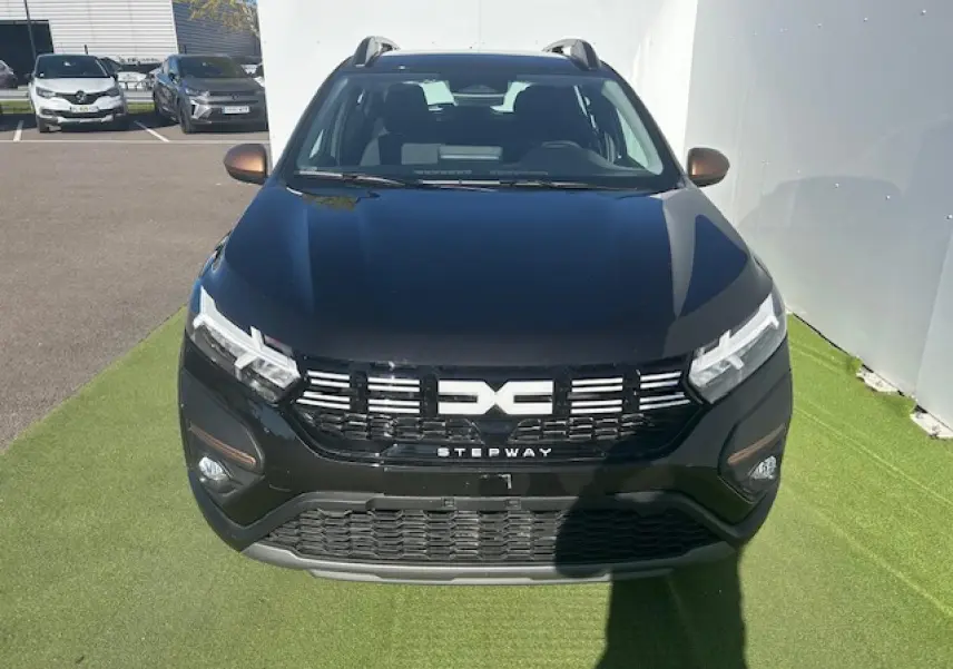 Vue avant d'une Dacia Sandero III Stepway noir nacré avec calandre noire et logo central blanc, sur fond clair.