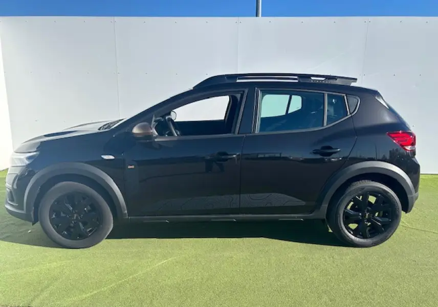 Vue de profil côté gauche d'une Dacia Sandero III Stepway noire nacrée avec jantes noires et barres de toit.
