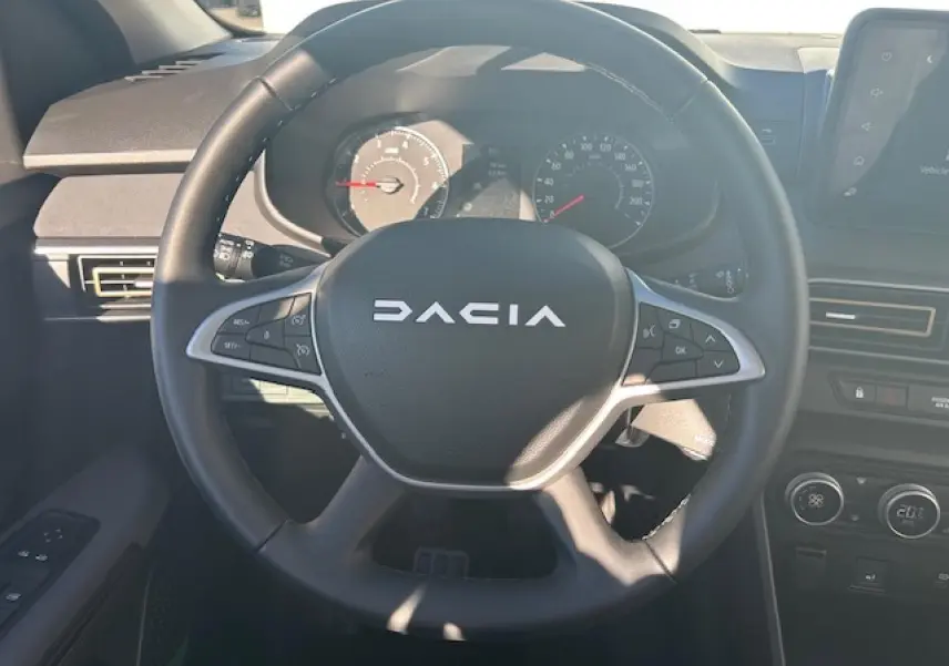 Vue intérieure centrée sur le volant noir du Dacia Sandero III Stepway avec tableau de bord et commandes visibles.