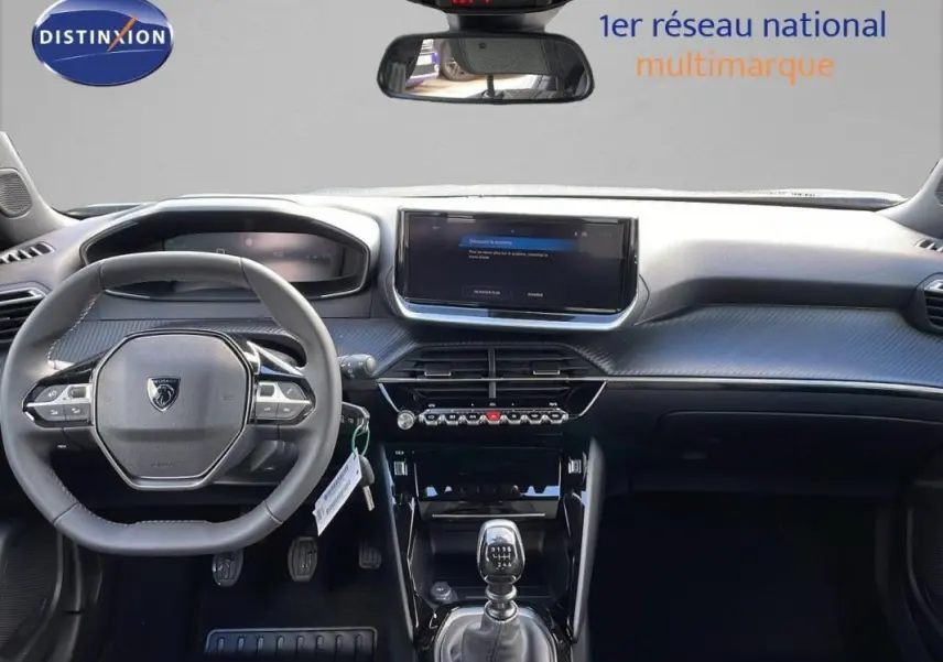 Intérieur Peugeot 2008 gris 2025 vu de face, volant cuir, écran tactile et levier de vitesse manuel visibles.