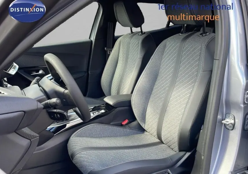 Vue intérieure côté conducteur du Peugeot 2008 gris 2025, mettant en valeur les sièges tissu et cuir avec volant cuir.