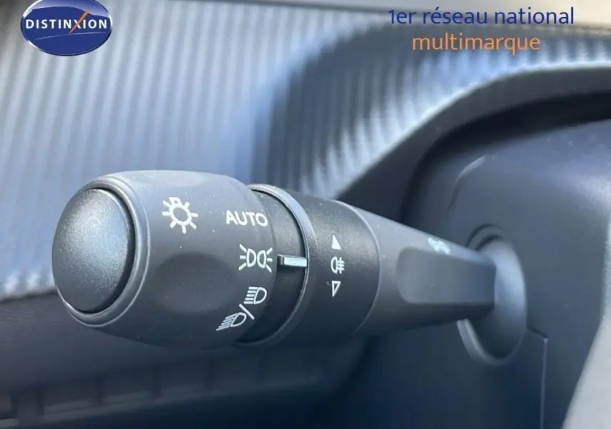 Gros plan sur la commande d’allumage automatique des feux dans un Peugeot 2008 gris, intérieur côté conducteur.