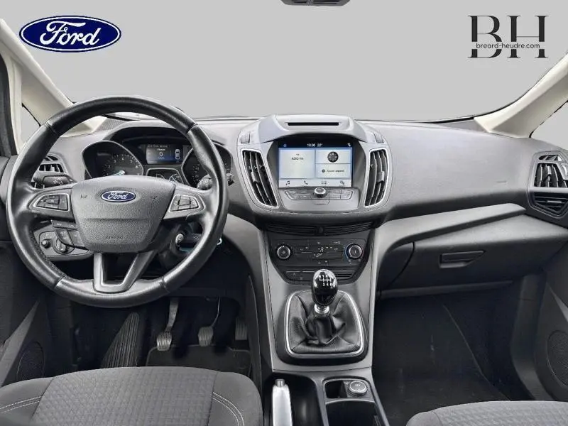 Vue intérieure avant du Ford C-MAX 2019 avec tableau de bord noir, volant cuir multifonction et écran tactile central.