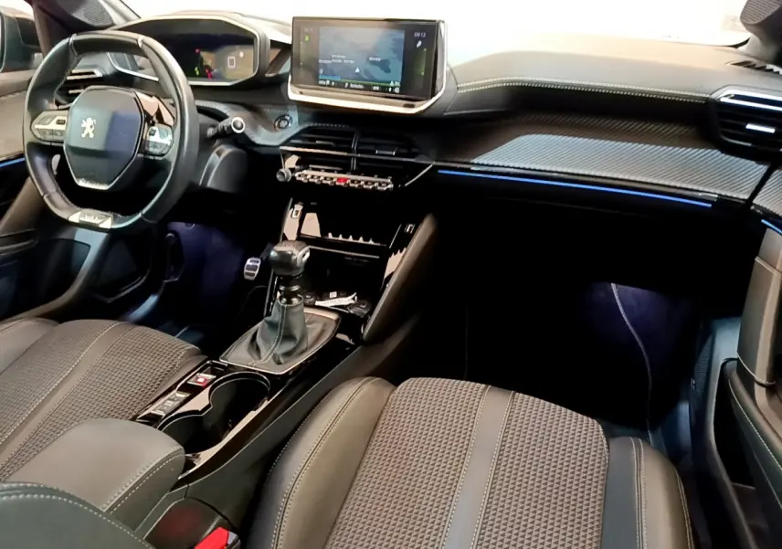 Intérieur avant droit de la Peugeot 208 GT Line 2020 avec tableau de bord noir, écran tactile et levier de vitesses manuel.