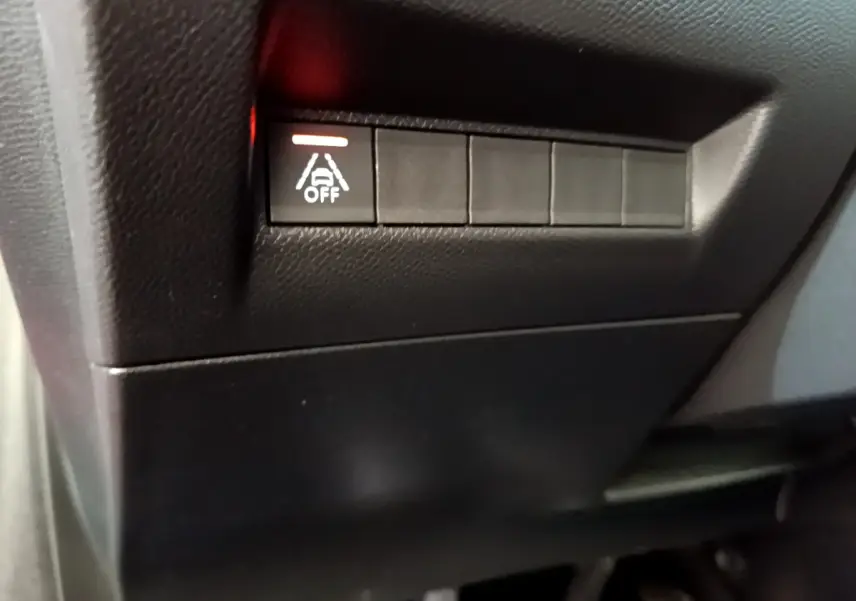 Gros plan sur le bouton de désactivation de l'assistance au maintien de voie dans l'habitacle noir d'une Peugeot 208 rouge