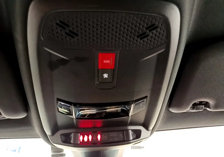Vue en gros plan du plafonnier avec bouton SOS et indicateurs de ceintures sur le toit intérieur d'une Peugeot 208 rouge