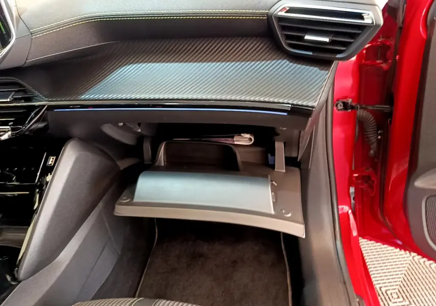 Vue intérieure côté passager du Peugeot 208 GT Line rouge 2020 avec boîte à gants ouverte et tableau de bord noir.