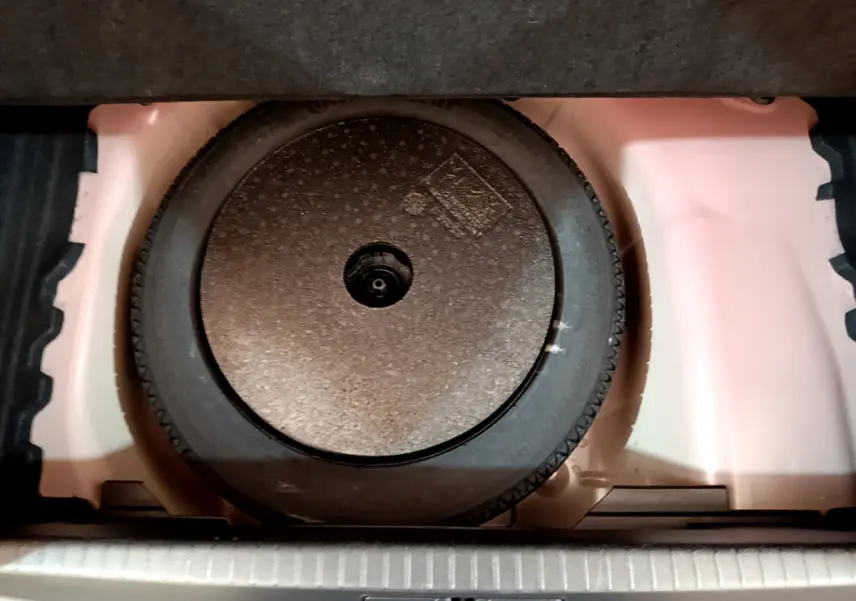 Roue de secours galette dans le coffre d'une Peugeot 208 BlueHDi 100 S&S GT Line rouge, vue en plongée.