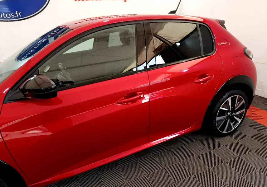 Profil côté gauche d'une Peugeot 208 GT Line rouge brillante avec jantes alliage et rétroviseurs noirs.