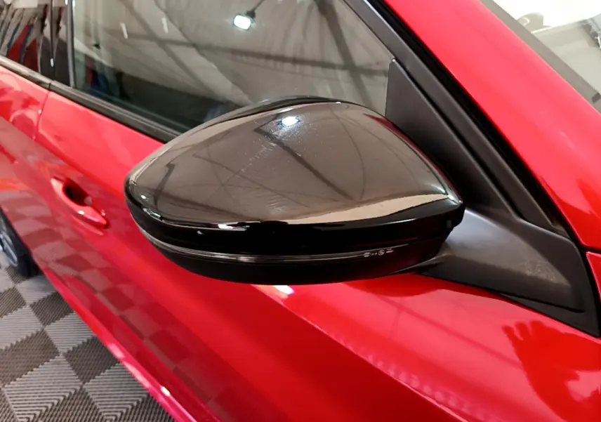 Rétroviseur noir côté gauche sur la porte rouge vif d'une Peugeot 208 GT Line 2020 vue en gros plan.