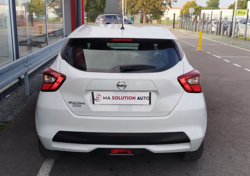 Vue arrière d'une Nissan Micra blanche 2019 avec feux arrière anguleux et logo visible sur parking.