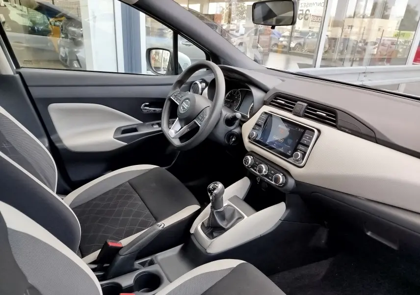 Intérieur avant droit de la Nissan Micra blanc 2019, volant multifonction, boîte manuelle et écran tactile central.