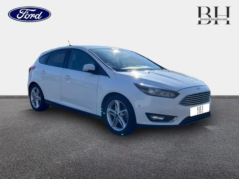 Ford Focus blanc glacier vue 3/4 avant droit, avec calandre chromée et jantes alliage cinq branches.