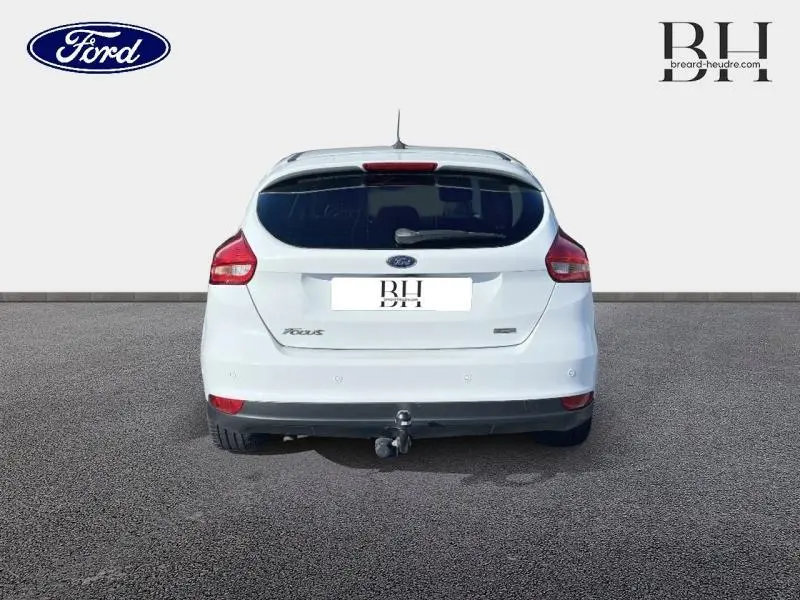 Vue arrière d'une Ford Focus blanc glacier de 2017 avec attelage et feux arrière rouges visibles.