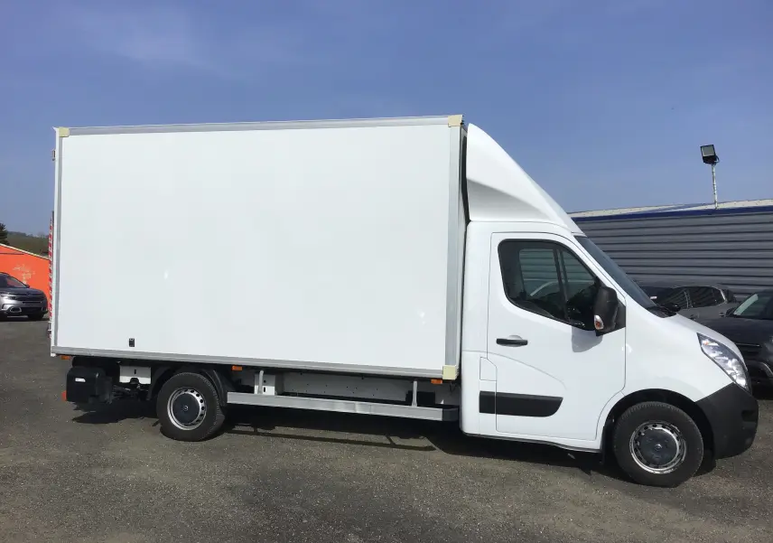 Vue de profil côté droit d'un Opel Movano blanc L3H1 avec caisse fermée et hayon, stationné en extérieur.