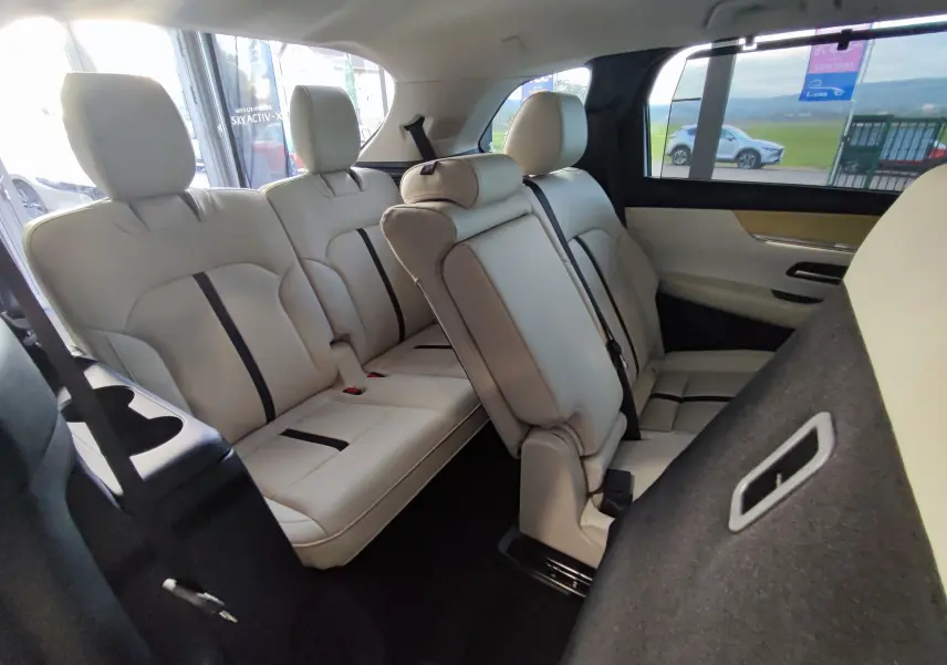 Vue intérieure des sièges arrière en cuir clair du Mazda CX-80 gris foncé, version 7 places, avec une rangée rabattue côté droit.