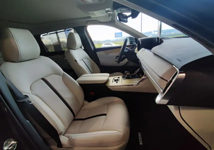 Intérieur clair du Mazda CX-80 2024 vu côté conducteur, sièges cuir beige avec bande noire et tableau de bord moderne.