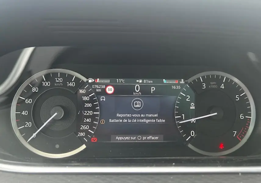 Tableau de bord numérique du Range Rover Evoque gris foncé, affichant vitesse, compte-tours et alertes.