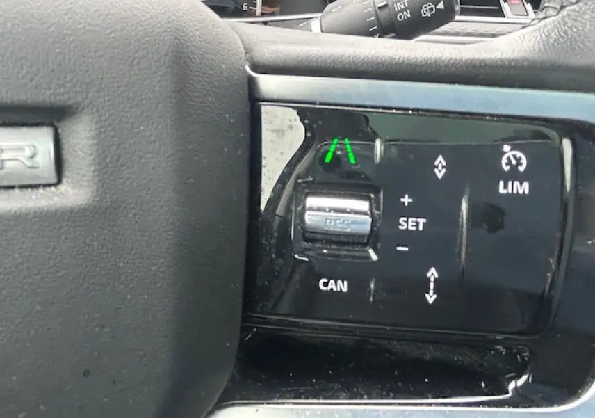 Gros plan sur les commandes de régulateur de vitesse au volant d'un Range Rover Evoque gris foncé 2022.