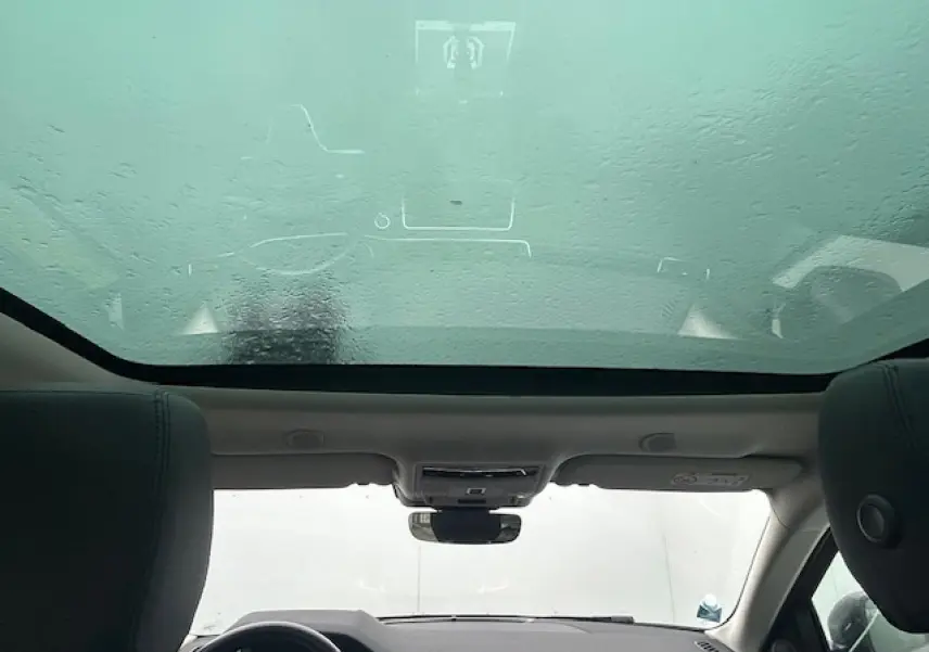 Vue intérieure du Range Rover Evoque gris foncé, mettant en valeur le toit panoramique fixe et le tableau de bord.