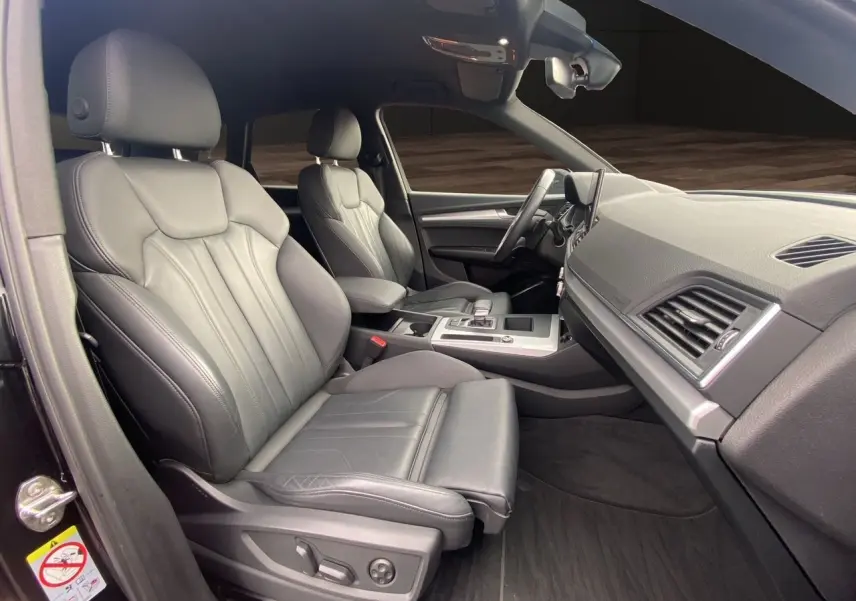 Vue intérieure côté gauche de l'Audi Q5 Business Edition S-Line 2022, sièges sport en cuir noir et tableau de bord moderne.
