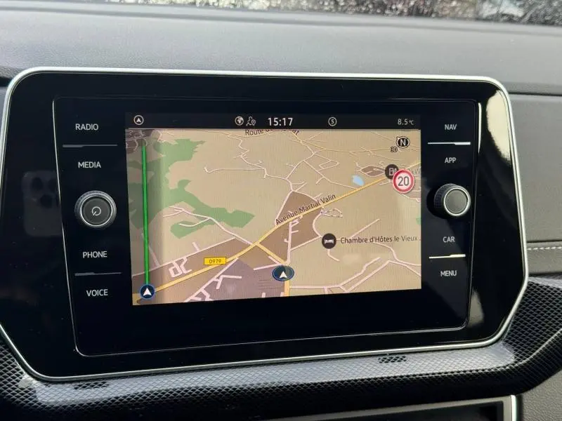 Écran tactile central du Volkswagen T-Cross 2025 affichant la navigation, entouré de boutons noirs et finition carbone.