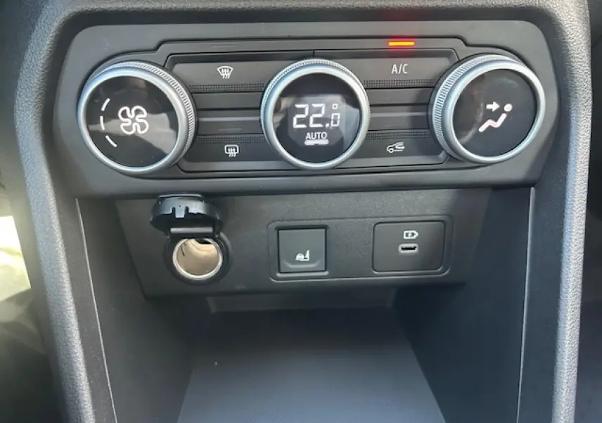Gros plan sur la console centrale de la Dacia Sandero III Stepway, montrant les commandes de climatisation et prises USB.