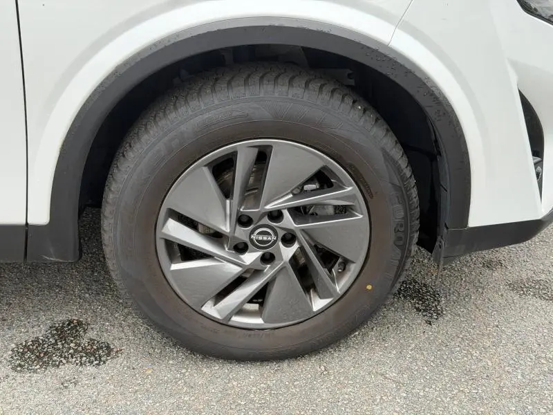 Gros plan sur la roue avant droite du Nissan Qashqai blanc nacré avec jante alu au design moderne.