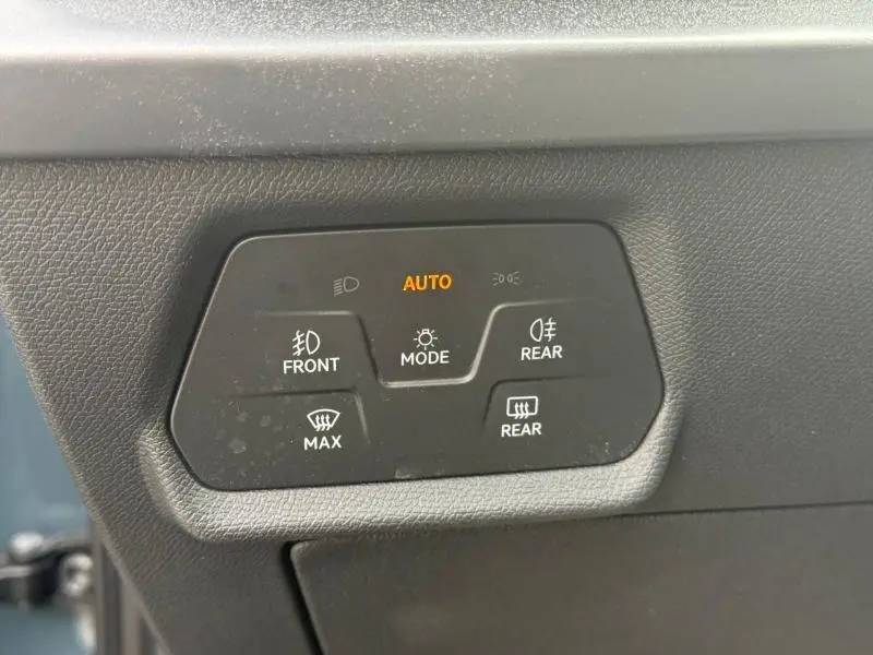 Panneau de commandes d’éclairage avec mode automatique allumé, sur tableau de bord noir d’une CUPRA Formentor bleu.