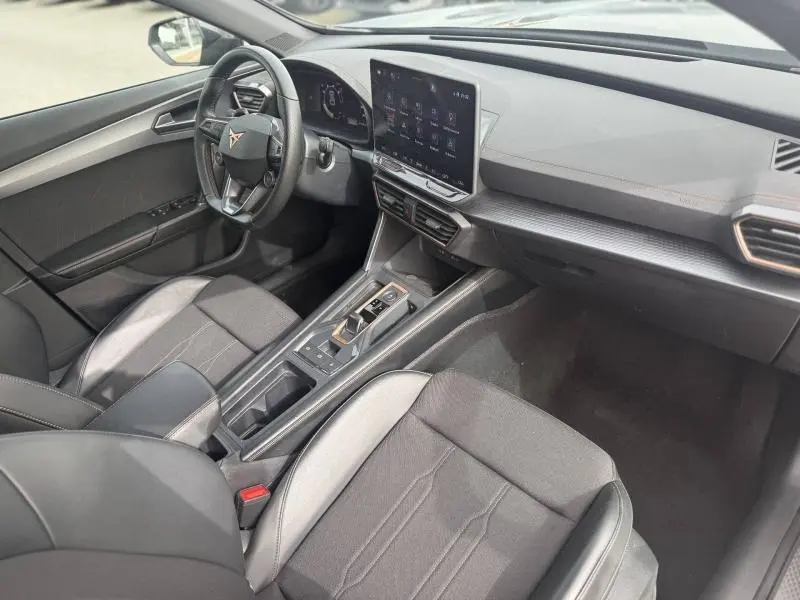 Vue intérieure côté conducteur de la CUPRA Formentor 2025, tableau de bord moderne avec écran tactile et sièges tissu noir.